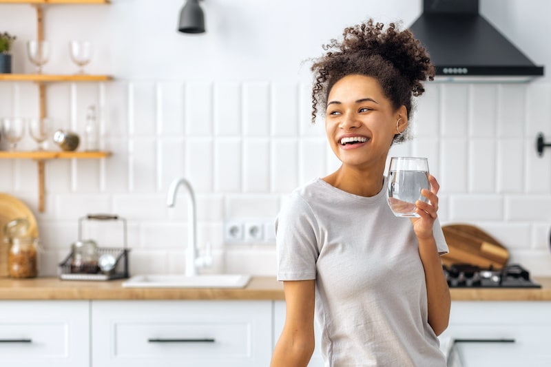 Woman holding a glass of water in a kitchen